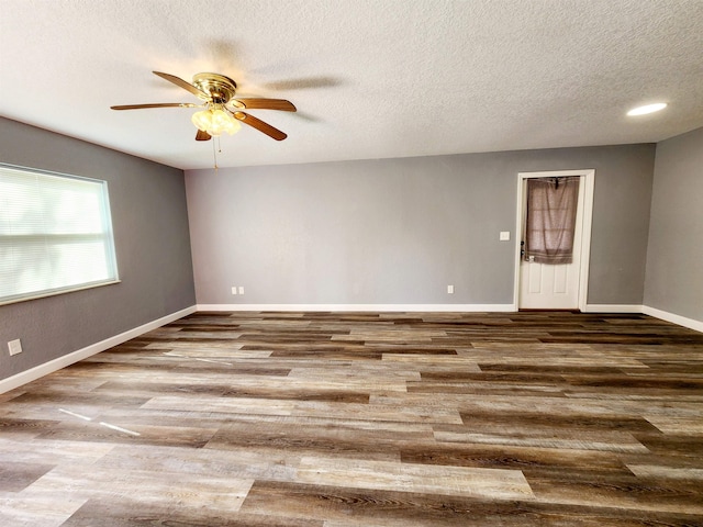 empty room with ceiling fan, wood-type flooring, and a textured ceiling