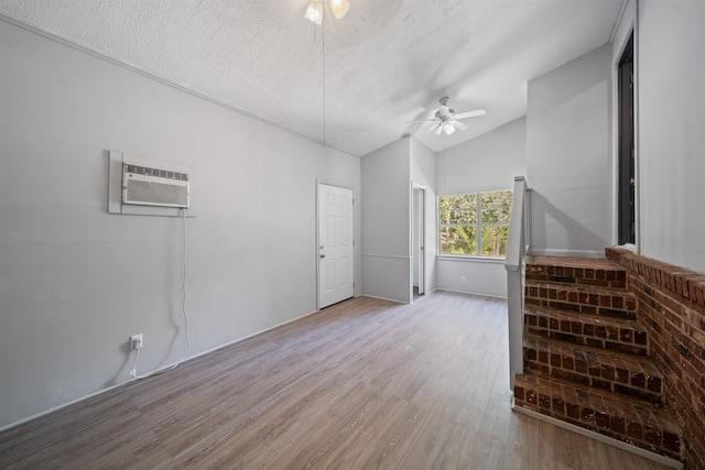 2401 Hideaway Ct, Tallahassee, FL 32303 - unfurnished living room with vaulted ceiling, a ceiling fan, an AC wall unit, light wood-type flooring, and a textured ceiling