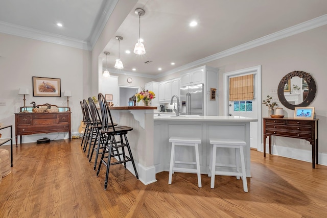 8555 Congressional Dr, Tallahassee, FL 32312 - kitchen featuring high end fridge, a breakfast bar, ornamental molding, a peninsula, and hanging light fixtures
