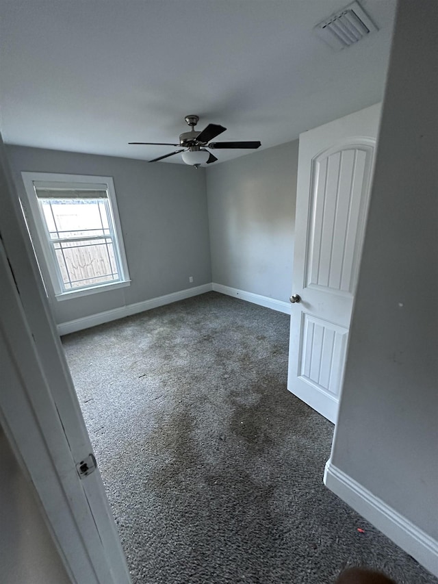 spare room with ceiling fan and dark colored carpet