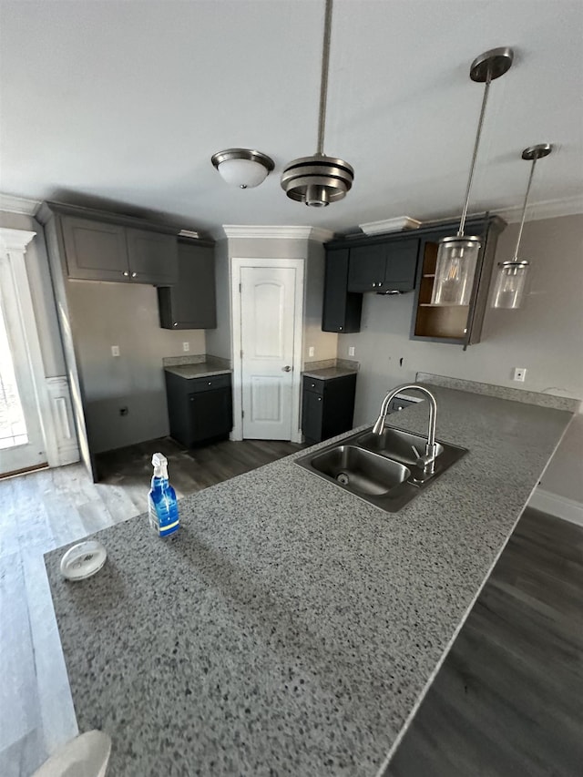 kitchen featuring sink, dark wood-type flooring, kitchen peninsula, crown molding, and pendant lighting