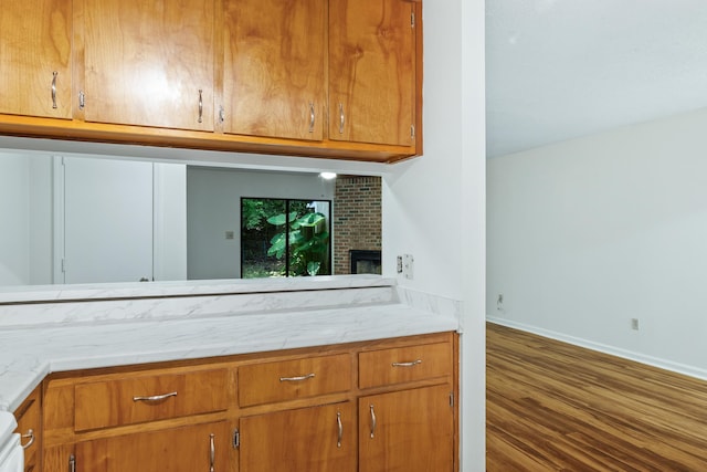 kitchen with a brick fireplace and dark wood-type flooring