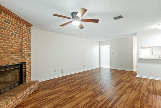 unfurnished living room featuring hardwood / wood-style floors, a fireplace, ceiling fan, and a textured ceiling