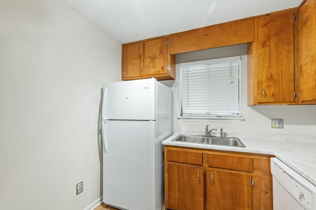 kitchen featuring a textured ceiling, white appliances, and sink