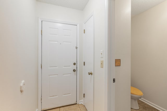 doorway to outside with light tile patterned floors and a textured ceiling