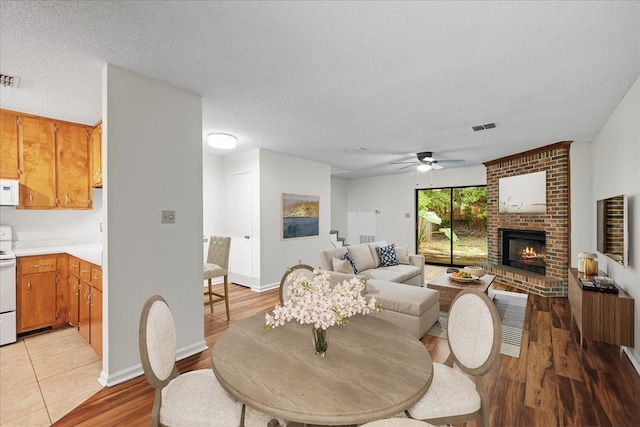 living room with ceiling fan, a fireplace, and a textured ceiling