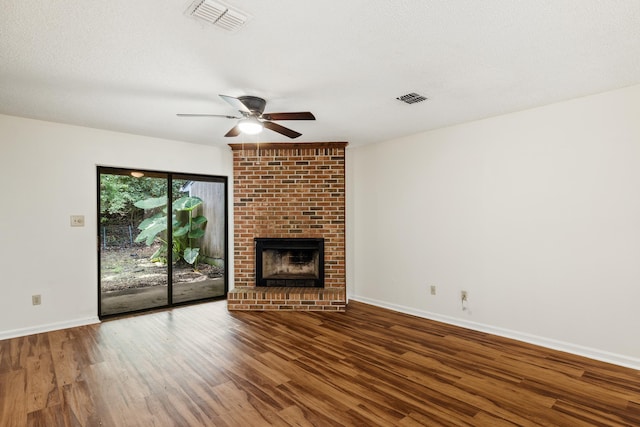 unfurnished living room featuring hardwood / wood-style flooring, ceiling fan, a textured ceiling, and a brick fireplace