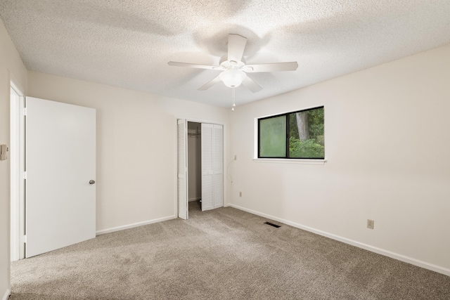 unfurnished bedroom with ceiling fan, light colored carpet, a textured ceiling, and a closet