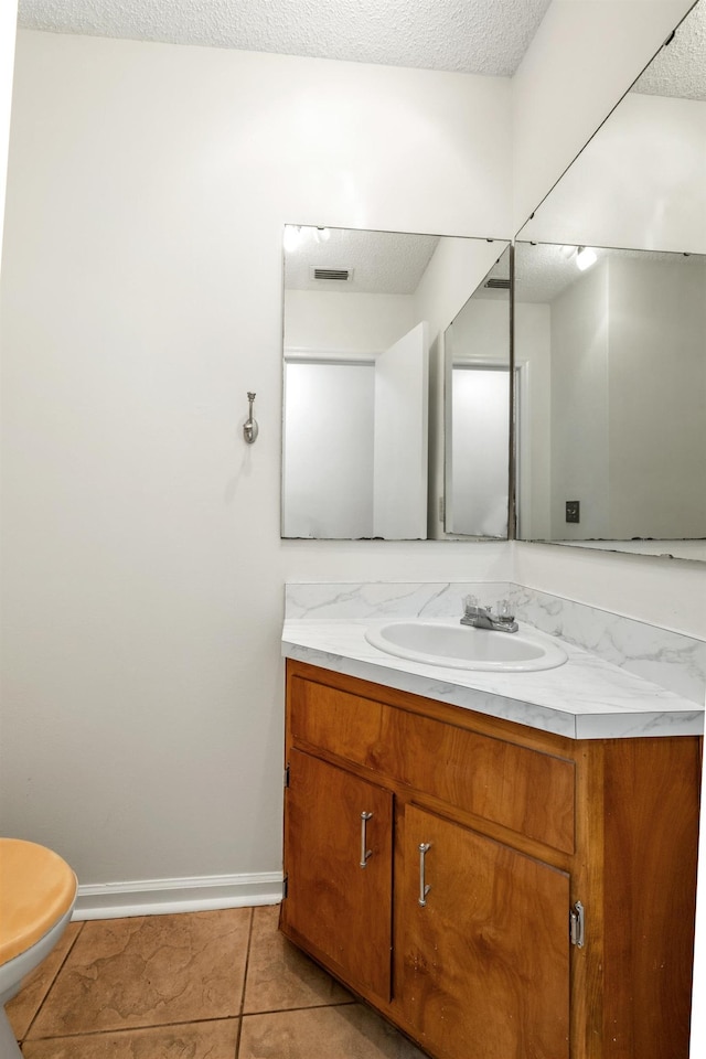 bathroom featuring tile patterned floors, vanity, a textured ceiling, and toilet