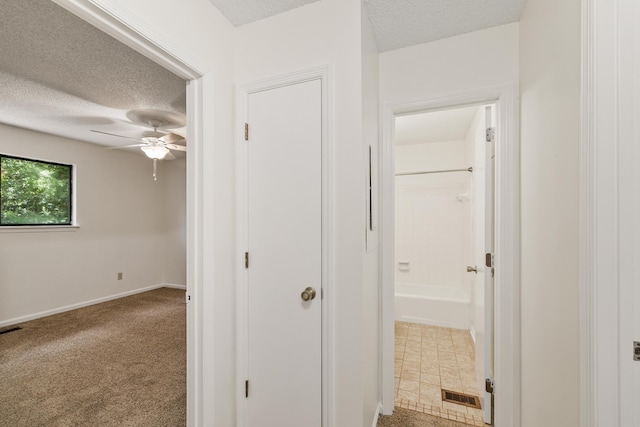 hall featuring carpet flooring and a textured ceiling