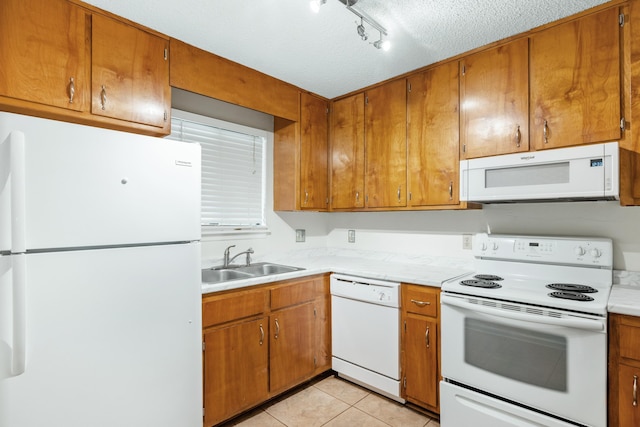 kitchen with white appliances, sink, rail lighting, light tile patterned floors, and a textured ceiling