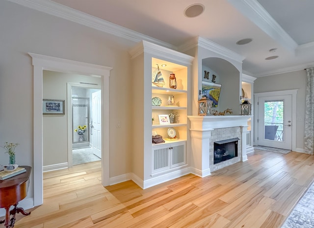 living area featuring ornamental molding, light wood-style flooring, built in shelves, and a fireplace