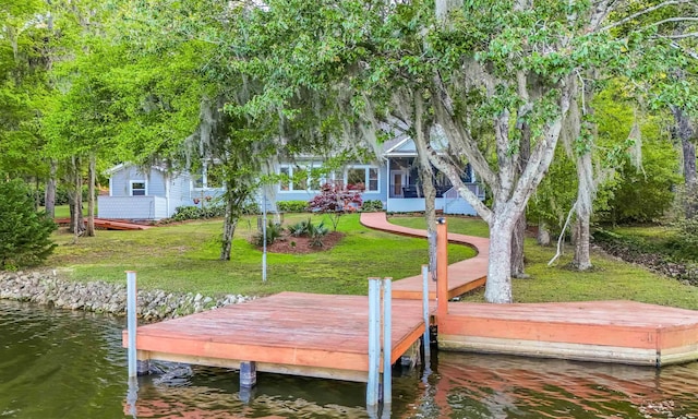view of dock with a lawn and a water view