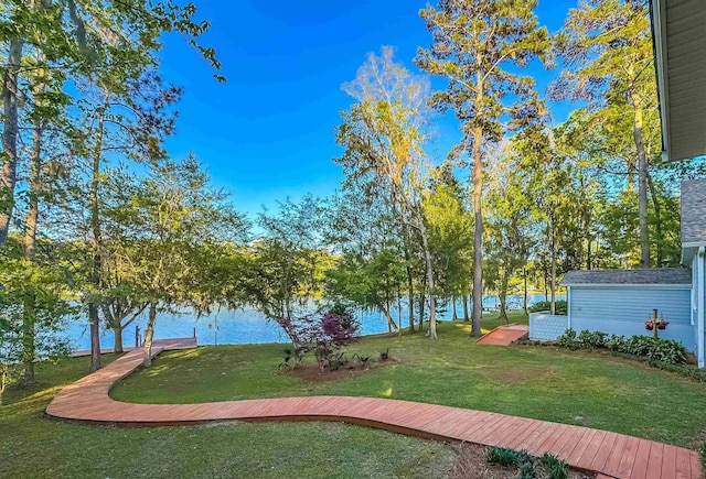 view of home's community with a yard, a water view, and an outbuilding