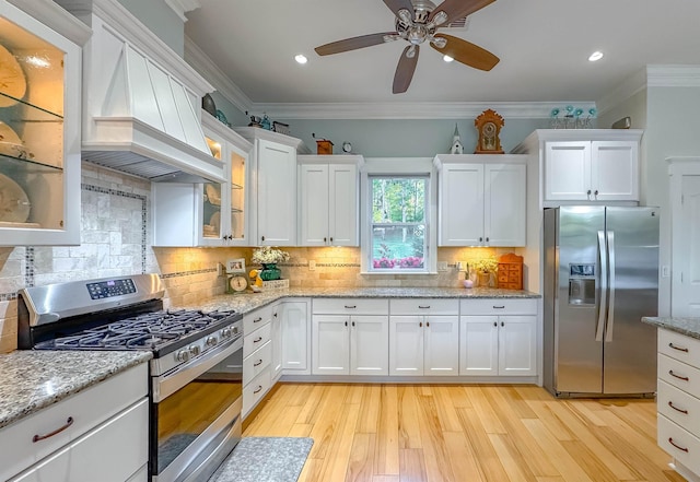 kitchen featuring appliances with stainless steel finishes, custom range hood, ornamental molding, and white cabinets