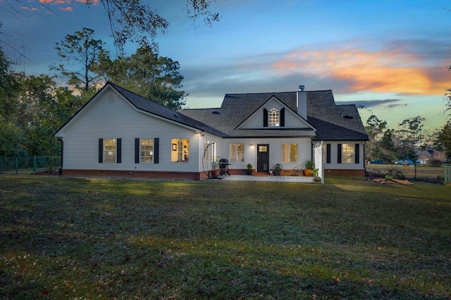 back house at dusk with a patio and a yard