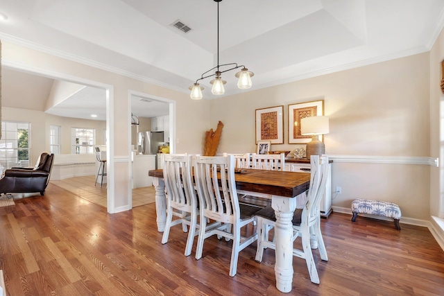 dining space with dark wood-type flooring and a tray ceiling