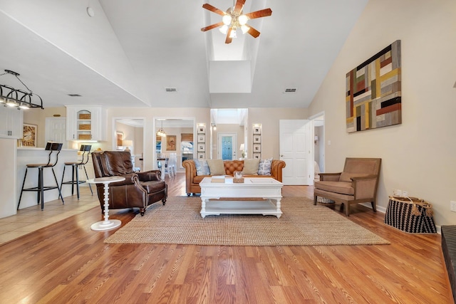 living room with ceiling fan, hardwood / wood-style floors, and vaulted ceiling