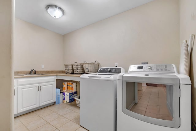 laundry room featuring washing machine and dryer, light tile patterned floors, cabinets, and sink