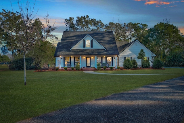 cape cod home with covered porch and a yard