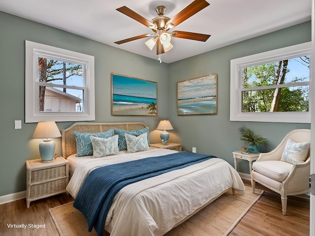 bedroom with hardwood / wood-style flooring, ceiling fan, and multiple windows