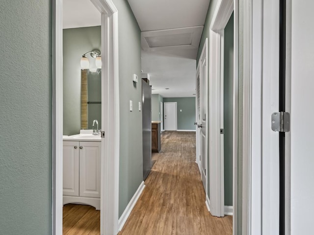 hallway featuring sink and light wood-type flooring