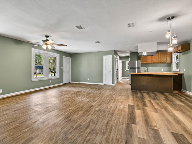 kitchen featuring ceiling fan, wood-type flooring, sink, and hanging light fixtures