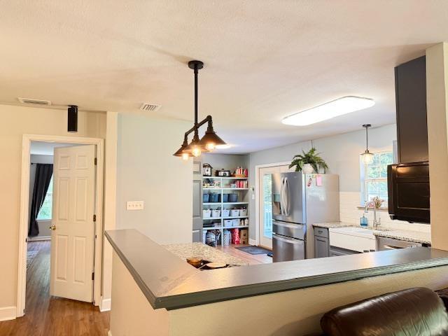 415 Hunters Trce, Crawfordville, FL 32327 - kitchen with stainless steel fridge, wood finished floors, pendant lighting, decorative backsplash, and light countertops