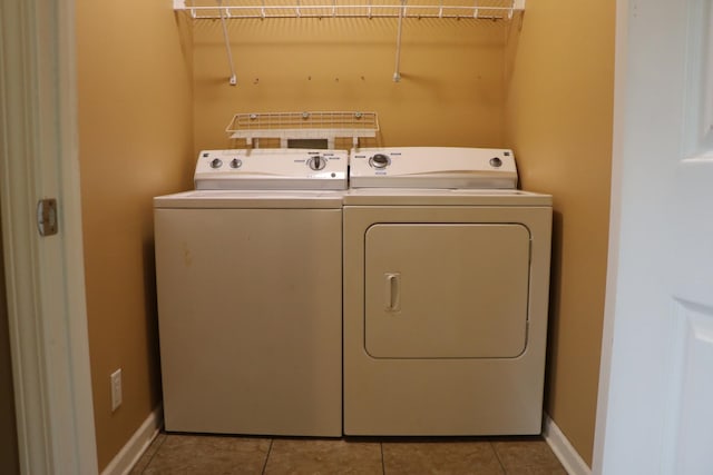 clothes washing area featuring washer and clothes dryer and light tile patterned flooring