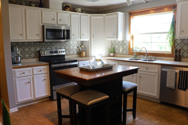 kitchen with backsplash, white cabinets, sink, and stainless steel appliances