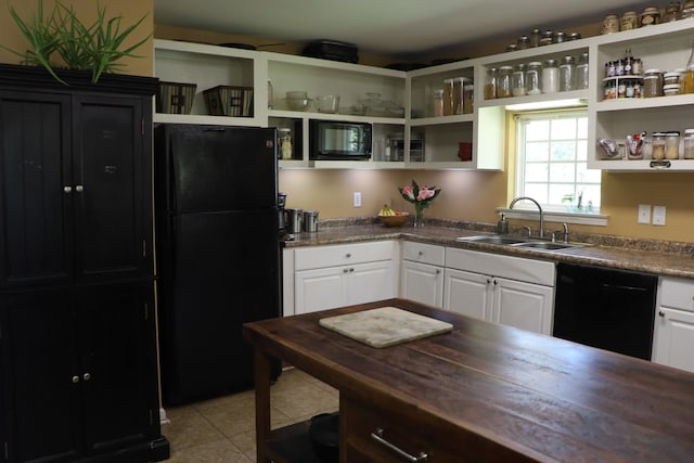 kitchen with light tile patterned floors, white cabinetry, sink, and black appliances