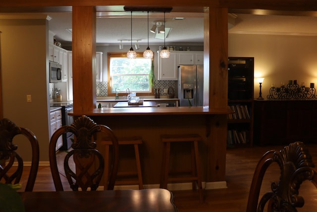 kitchen with white cabinetry, appliances with stainless steel finishes, backsplash, dark wood-type flooring, and pendant lighting