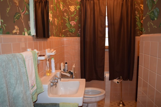 bathroom with toilet, tile walls, and sink