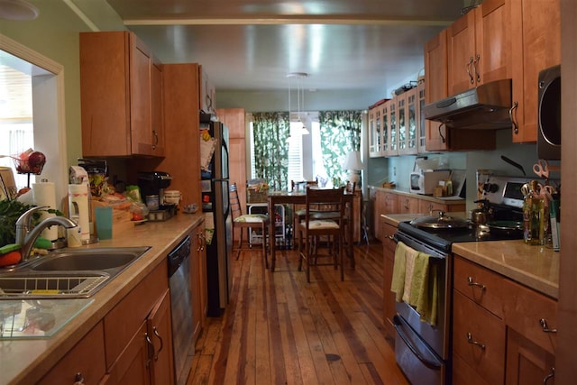 kitchen featuring stainless steel appliances, hanging light fixtures, hardwood / wood-style flooring, and sink