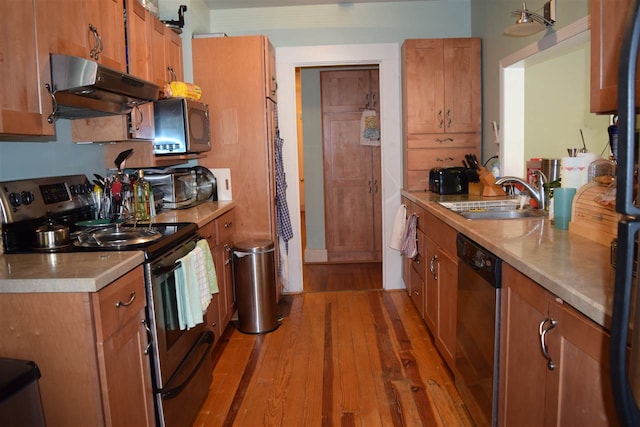 kitchen featuring hardwood / wood-style flooring, sink, stainless steel appliances, and hanging light fixtures