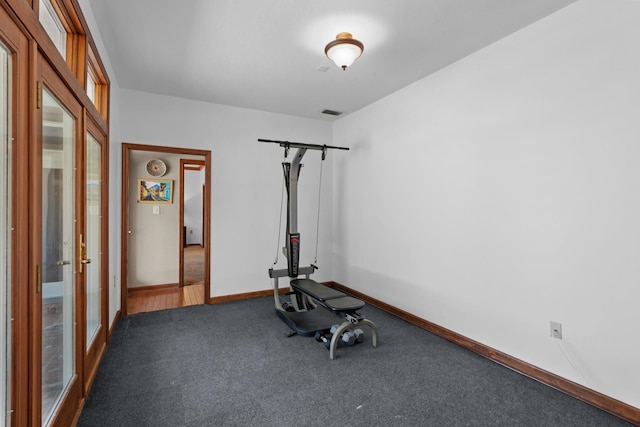 workout room featuring french doors and dark carpet