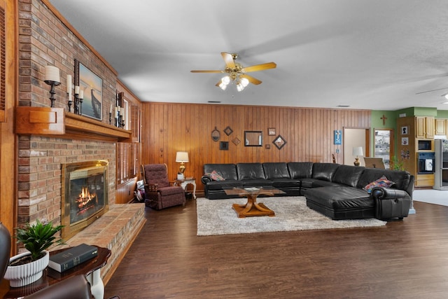 living room featuring a fireplace, dark hardwood / wood-style flooring, wooden walls, and ceiling fan