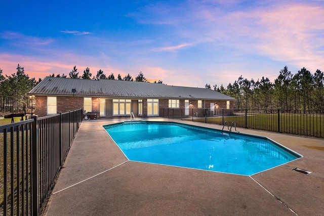 pool at dusk featuring a patio