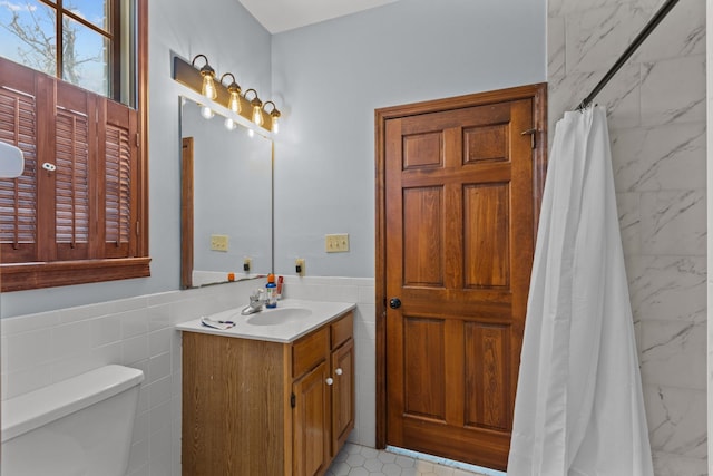 bathroom with walk in shower, vanity, tile walls, and toilet