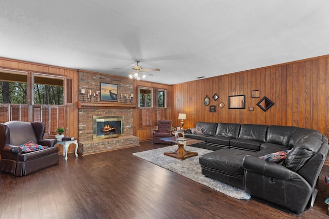 living room featuring a fireplace, wooden walls, dark hardwood / wood-style floors, and ceiling fan