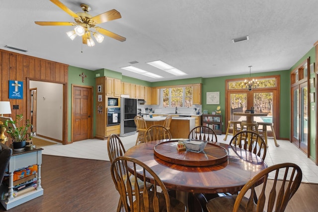 dining space with a textured ceiling, ceiling fan with notable chandelier, and light hardwood / wood-style flooring