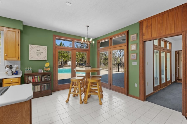 dining area with light tile patterned floors, french doors, a notable chandelier, and a healthy amount of sunlight