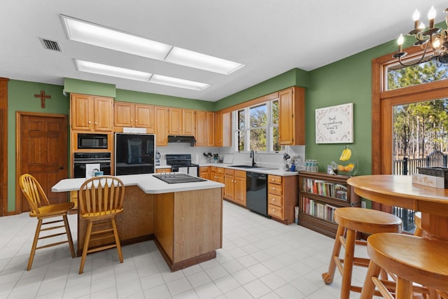 kitchen with sink, black appliances, a kitchen bar, an inviting chandelier, and decorative backsplash