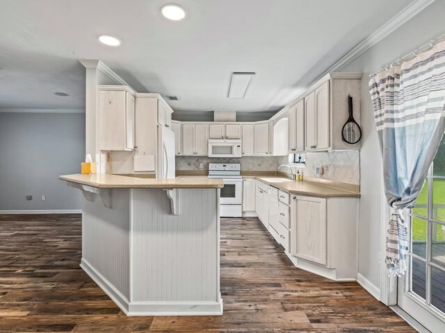 kitchen featuring a kitchen bar, sink, dark hardwood / wood-style floors, and white appliances