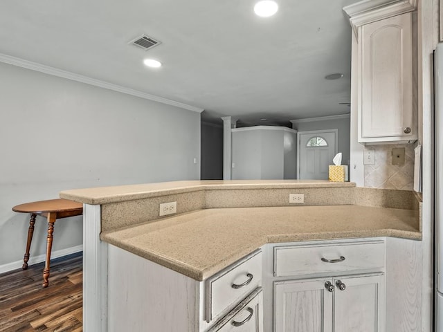 kitchen with crown molding, dark hardwood / wood-style floors, tasteful backsplash, white cabinetry, and kitchen peninsula