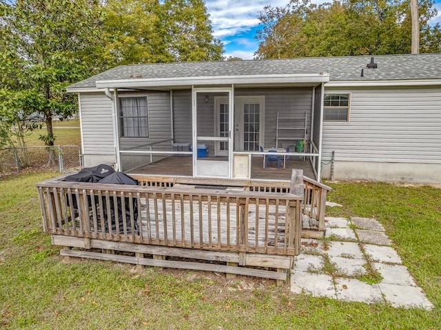 wooden deck featuring a lawn and a sunroom