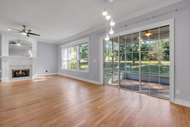 unfurnished living room with a fireplace, hardwood / wood-style floors, ceiling fan, and crown molding