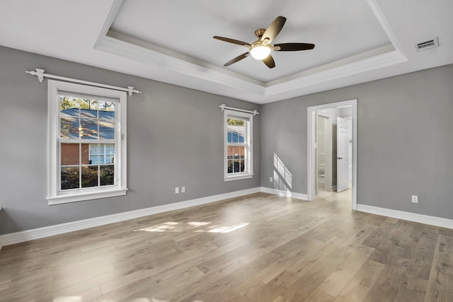 spare room with ceiling fan, light hardwood / wood-style flooring, and a tray ceiling