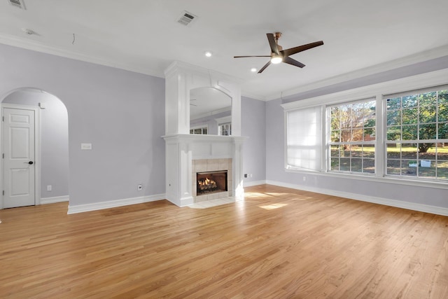 unfurnished living room featuring a tiled fireplace, ceiling fan, light hardwood / wood-style floors, and crown molding