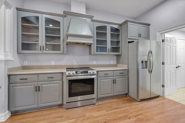 kitchen featuring appliances with stainless steel finishes, gray cabinetry, light hardwood / wood-style flooring, and custom range hood